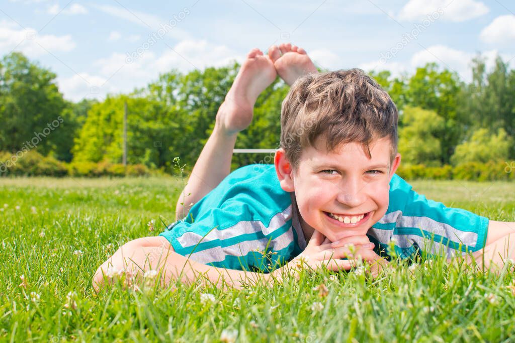 smiling boy lying on the grass on his stomach