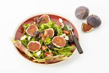karışık salata incir, domates, koyun peyniri, rulo, pişmiş jambon bir kırmızı plaka, beyaz arka plan üzerinde hizmet