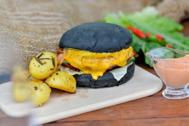 Köy patatesi ve baharatlı soslu siyah çizburger.