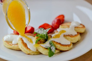 Çilek, meyve reçeli ve ekşi kremayla servis edilen peynirli krep.