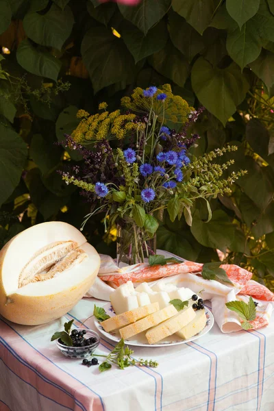 Stilleven met meloen en boeket van korenbloemen op wit tafelkleed — Stockfoto