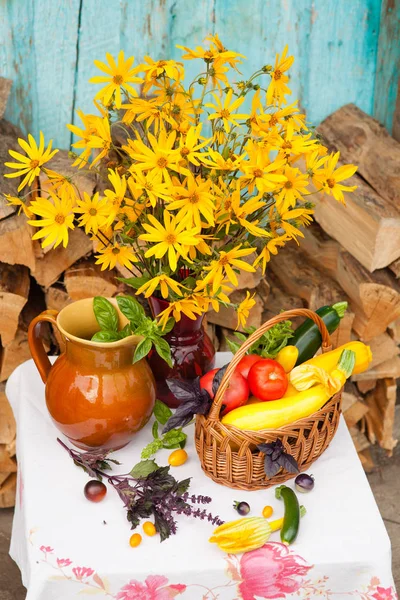 Boeket van bloemen en mand met herfst oogst van seizoensgroenten — Stockfoto