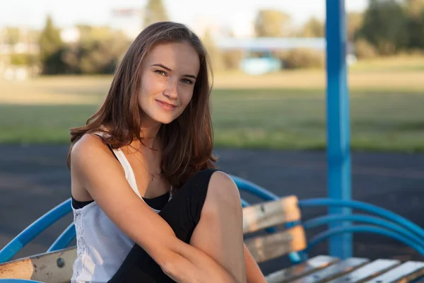 Pretty girl sits on bench in summer park — Stock Photo, Image
