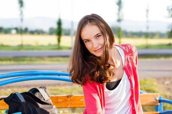 Pretty girl sits on bench in summer park — Stock Photo, Image