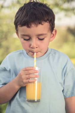 Çocuk evlat küçük çocuk portakal suyu içecek açık vintage bir görünüm portre biçiminde cam açık havada dışarıda içme