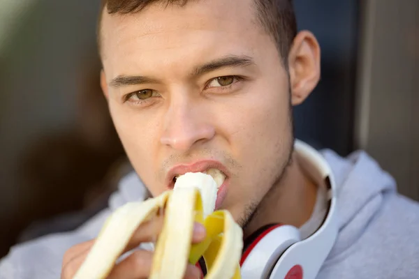 Giovane uomo latino mangiare banana frutta corridore sport invernali in esecuzione — Foto Stock