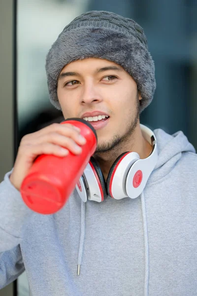 Genç latin adam su içme portresi kış koşusu formatında — Stok fotoğraf