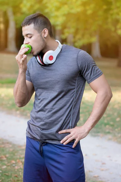 Läufer junger lateinischer Mann isst Apfel Porträtformat Joggen — Stockfoto