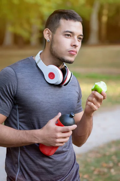 Runner latin man mangiare mela verticale formato corsa jogging sp — Foto Stock
