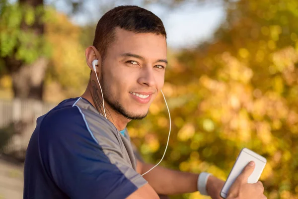 Young latin man listening to music runner running jogging autumn — Stock Photo, Image