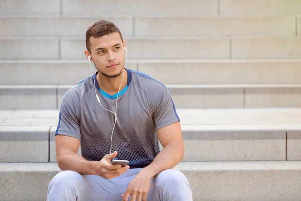 Слушать музыку молодой латиноамериканец смотрит вверх смартфон слушать — стоковое фото