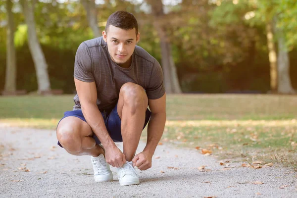 Young latin man tying lace shoelace shoes runner ready preparing