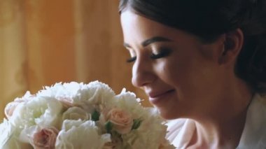 Genç gelin bir buket çiçek ile lüks otel cam kenarında oturan
