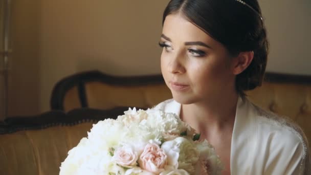 Giovane sposa è seduta alla finestra in un hotel di lusso con un mazzo di fiori — Video Stock