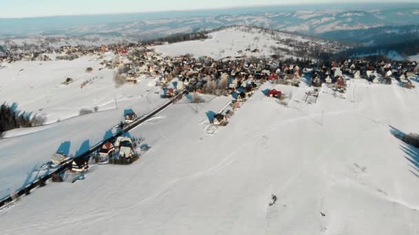 日差しの中での周りの雪が多いフィールドの田舎の小さな村の空撮 — ストック動画