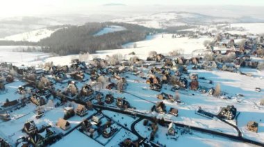 Drone görünümünü yazlıklar ve parlak güneş ışığı ile dağlarda karlı arazide evleri