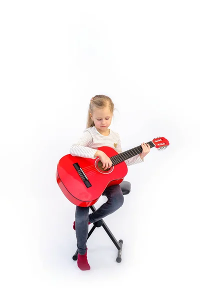 litle sarışın kız oturur ve kırmızı gitar çalar
