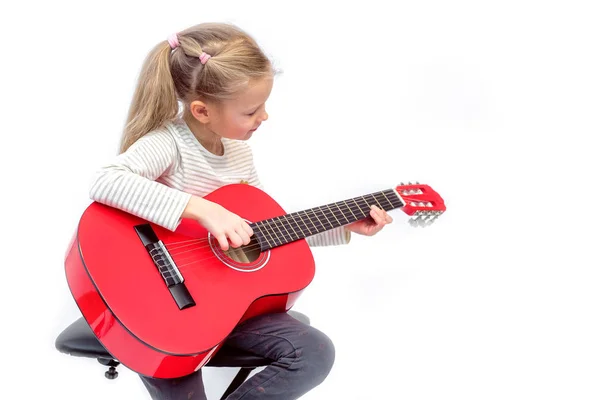 litle sarışın kız oturur ve kırmızı gitar çalar
