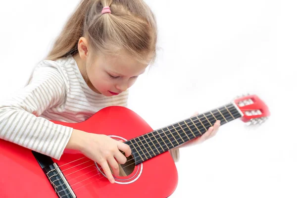litle sarışın kız oturur ve kırmızı gitar çalar