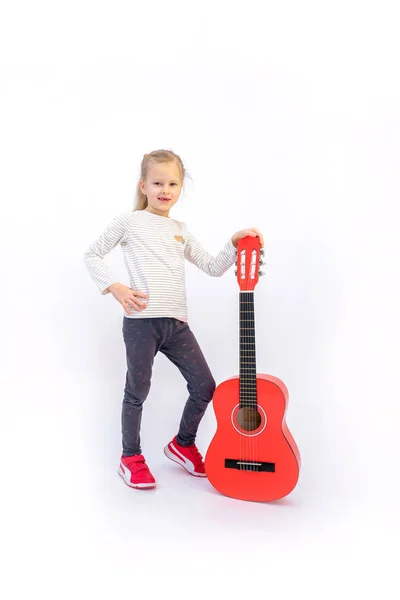 litle sarışın kız oturur ve kırmızı gitar çalar