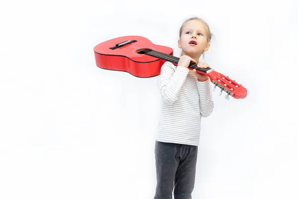 litle sarışın kız oturur ve kırmızı gitar çalar