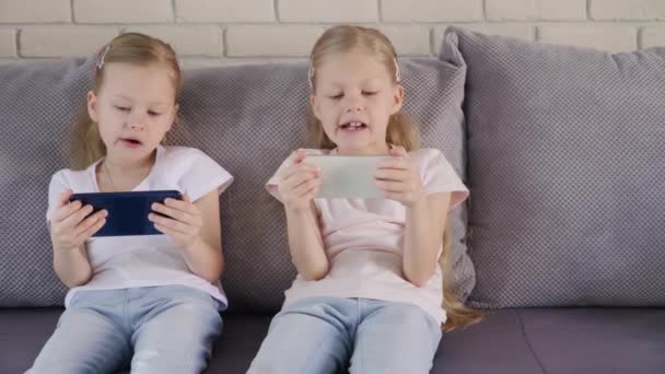 Twins using smatphones on sofa — Wideo stockowe