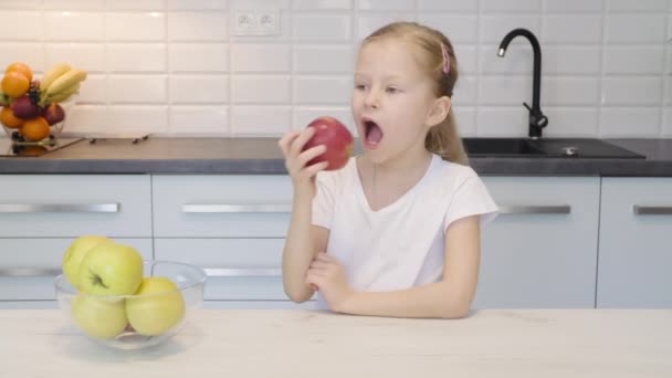 Klein meisje eten Apple in de keuken — Stockvideo