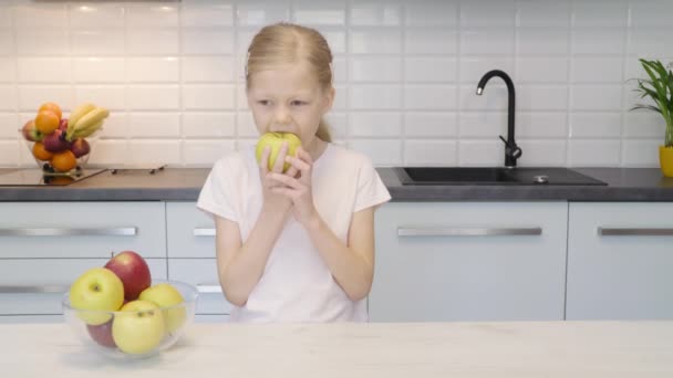 Niña comiendo manzana en la cocina — Vídeos de Stock