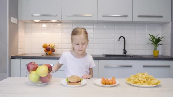 小さな女の子は台所で食べ物を選択します — ストック動画