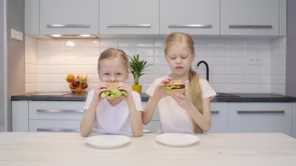 Gêmeos comendo hambúrgueres na cozinha — Vídeo de Stock