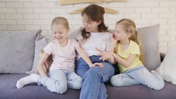 Madre cosquillas niñas en el sofá — Vídeos de Stock
