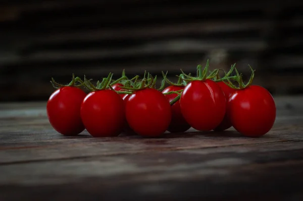 Small red cherry lying  tomatoes on rustic background. Cherry tomatoes on the vine. Closeup healthy food vegetables photo