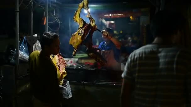 バンルン町のナイト マーケット 唾を吐きにポークのグリル 女性は ローストに掛かっている豚の つの大きな部分から肉の部分をスライスします 2018 年カンボジア バンルン町 — ストック動画