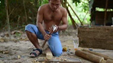 Kamboçyalı adam ahşap ev inşaat yanında balta gibi araçlar kullanılarak geleneksel yol oluşturmak için hazırlar. Diğer ahşap kiriş ile uygun ahşap kiriş deşmek. 28 Kasım 2017, Koh Rong Samloem. Kamboçya. 