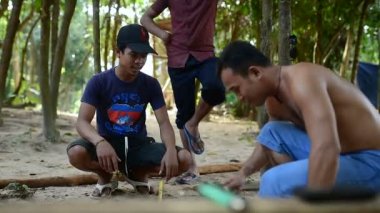 Kamboçyalı adam ahşap ev inşaat yanında balta gibi araçlar kullanılarak geleneksel yol oluşturmak için hazırlar. Diğer ahşap kiriş ile uygun ahşap kiriş deşmek. 28 Kasım 2017, Koh Rong Samloem. Kamboçya. 