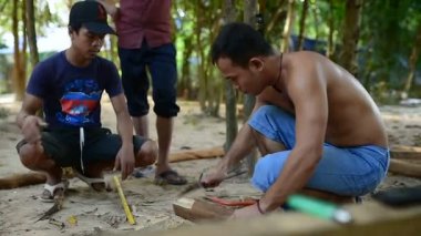 Kamboçyalı adam ahşap ev inşaat yanında balta gibi araçlar kullanılarak geleneksel yol oluşturmak için hazırlar. Diğer ahşap kiriş ile uygun ahşap kiriş deşmek. 28 Kasım 2017, Koh Rong Samloem. Kamboçya. 