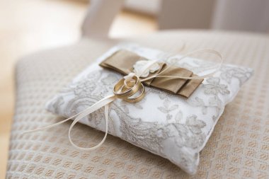 Altın alyanslar küçük süslü bir yastıkta yatıyor. 