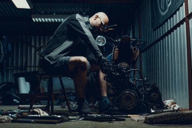 Garajda motorunu tamir eden genç bir adam. Motosiklet motoru parçalanmış. Motor sermayesi tamiri. 16 vana ve 4 silindir.. 