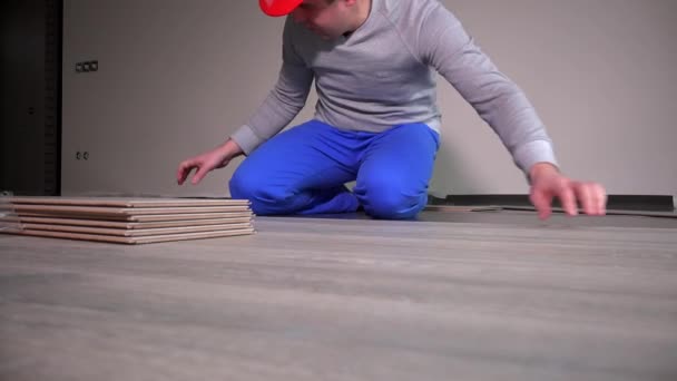 Skilled builder with red hard hat lay laminate flooring at construction site — Stock Video