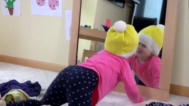 Söt prinsessa flicka med gul hatt kysser sig själv i en spegel. Barnet har roligt — Stockvideo