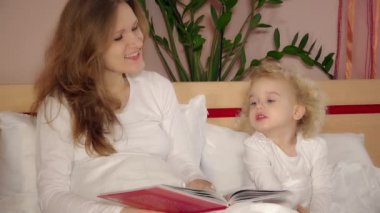 Mutlu kucakladı anne ve sevimli kız uyku önce kitap okuma