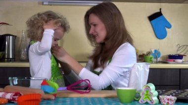 Sevgi dolu bir anne yürümeye başlayan çocuk kızı kız önlük mutfak koymak.