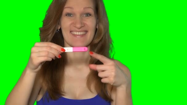 Возбужденная женщина показывает тест на беременность с двумя полосками и смотреть в камеру — стоковое видео