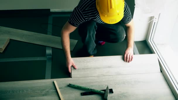 Onherkenbaar mannelijke werknemer met gele helm vloerplanken installeren — Stockvideo