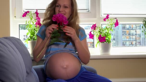 Mulher grávida feliz com barriga grande segurando flor peônia vermelha — Vídeo de Stock