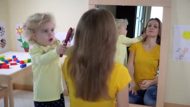 Chica peinando el pelo de la mujer delante del espejo — Vídeos de Stock