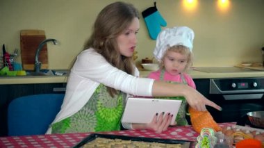 yardımcı kız annesi kurabiye pişirme ile yardım. Tablet bilgisayar kadınla.