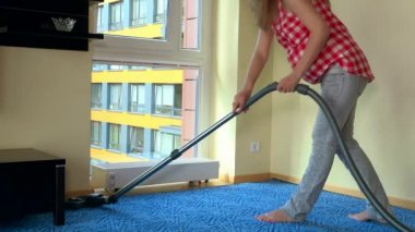 Mutlu hamile kadın elektrikli süpürge ile çalışmak ve dinlenmek için radyatör üzerinde oturmak