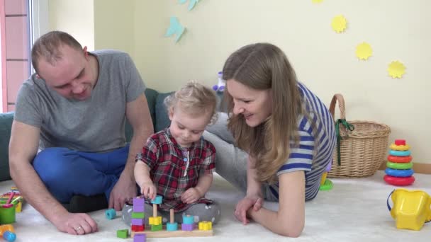Familia joven con niña jugar con juguete infantil en la habitación. 4K — Vídeo de stock