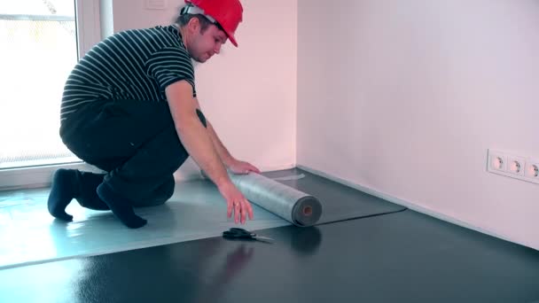 Homem trabalhador profissional que estabelece underlay para instalação piso laminado — Vídeo de Stock